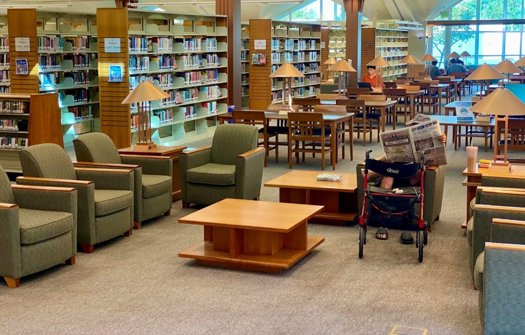 Library seating area with bookshelves and tables.