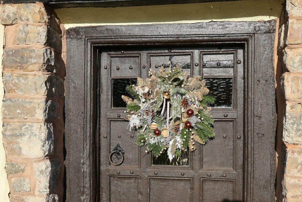 A festive wreath hangs on a rustic wooden door.