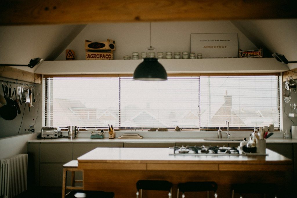A bright kitchen with a wooden island and large window.