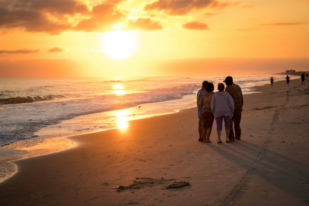 Four people watching a vibrant sunset over the ocean.