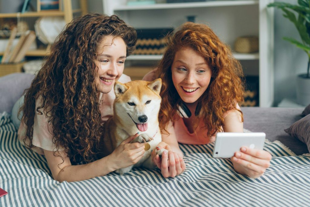 two women laying on a bed with a dog