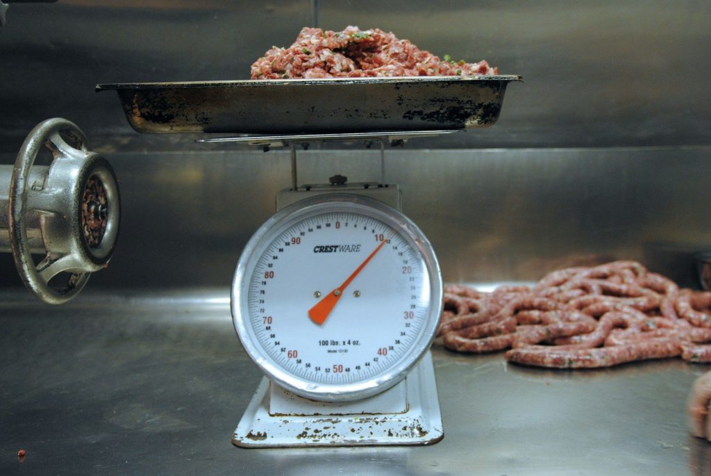Ground meat on a scale next to sausages