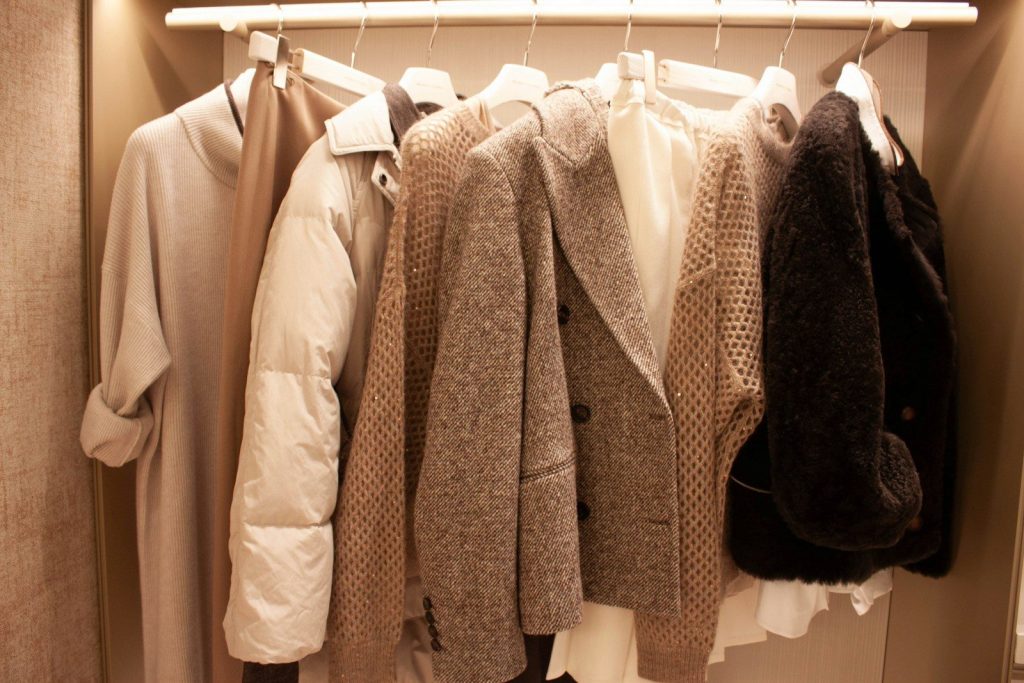 Various coats and jackets hanging on a closet rack.