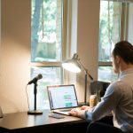 man in white dress shirt sitting on chair using laptop computer