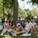 a group of people sitting on top of a lush green park