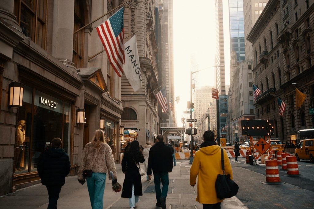 A group of people walking down a street next to tall buildings