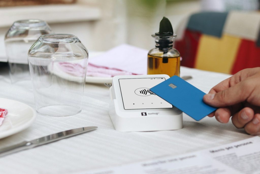 A person holding a credit card at a table