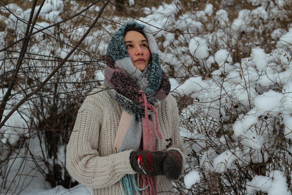 woman in brown knit sweater standing near bare trees during daytime