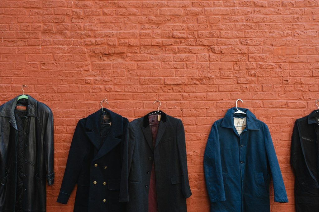 Five coats hanging on a brick wall