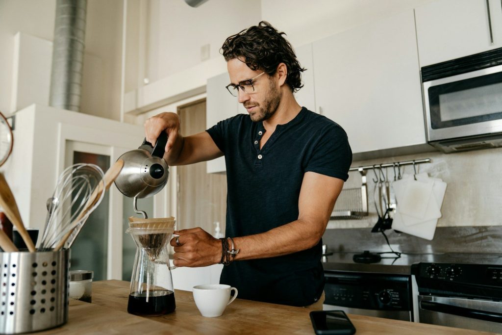 man in blue crew neck t-shirt pouring water on white ceramic teacup