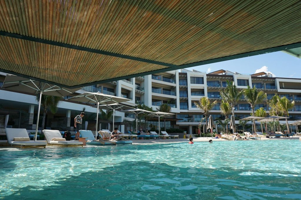 a pool with people in it by a building with a roof
