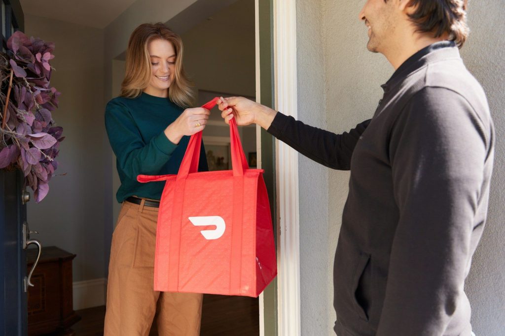 a woman holding a red shopping bag while standing next to a man