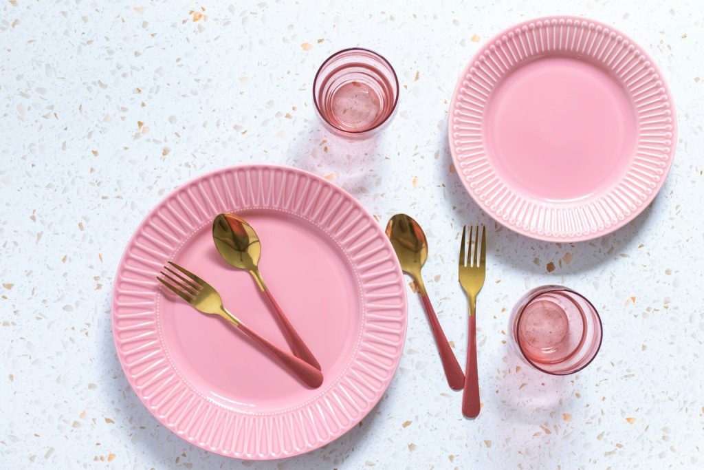a pink table setting with utensils and glasses