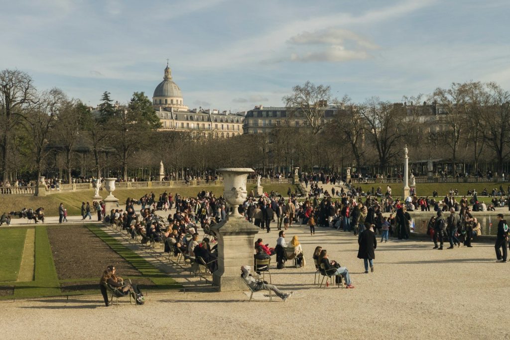 People relaxing in a park with ornate buildings behind.