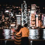 man in yellow shirt and black and white striped pants sitting on dock during night time