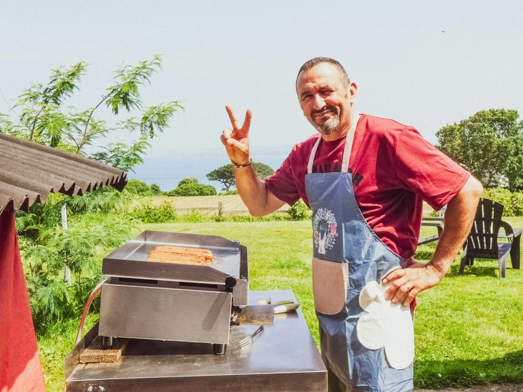 Man grilling hot dogs and giving peace sign