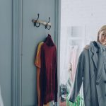 Woman trying on a coat in a mirror.