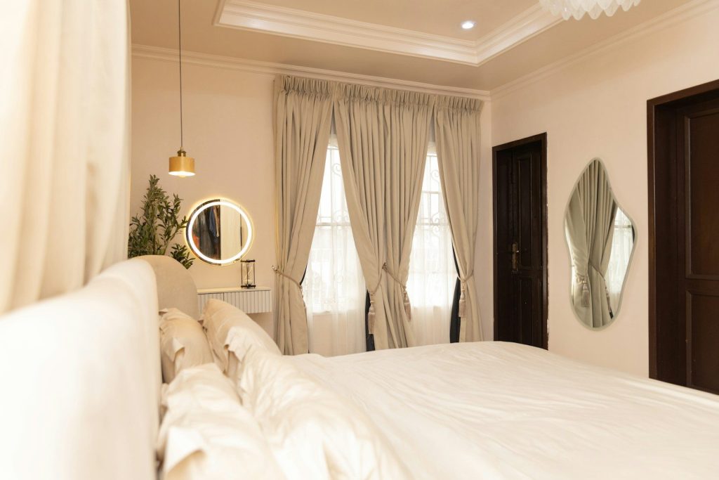A bright bedroom with a large bed, windows, and mirrors.