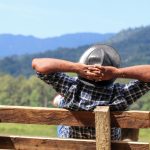 a man resting his head on a wooden fence