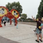 People gather near a large mickey mouse ears archway.
