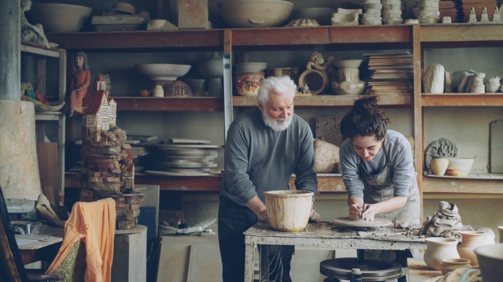 A potter and an apprentice work in a workshop.