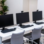 three computer monitors sitting on top of a white table