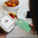 A person holding a credit card next to a bowl of food