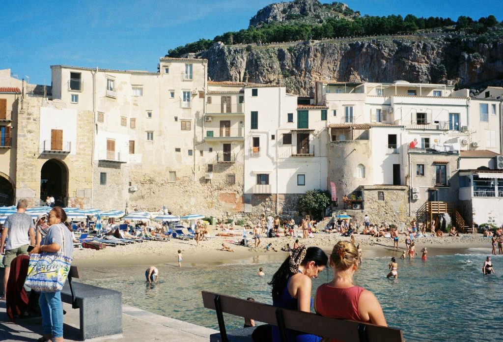 Beach scene with buildings, mountain, and people.
