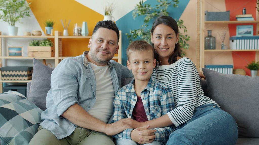 A happy family of three sitting on a couch.