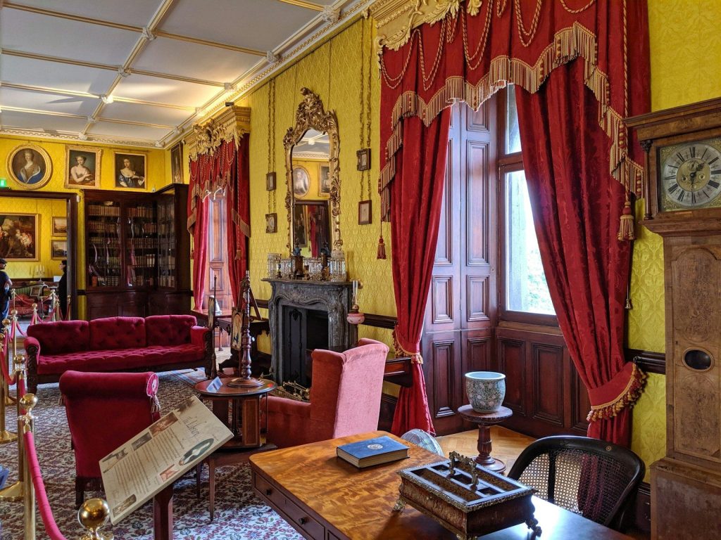 An ornate room with antique furniture and red curtains