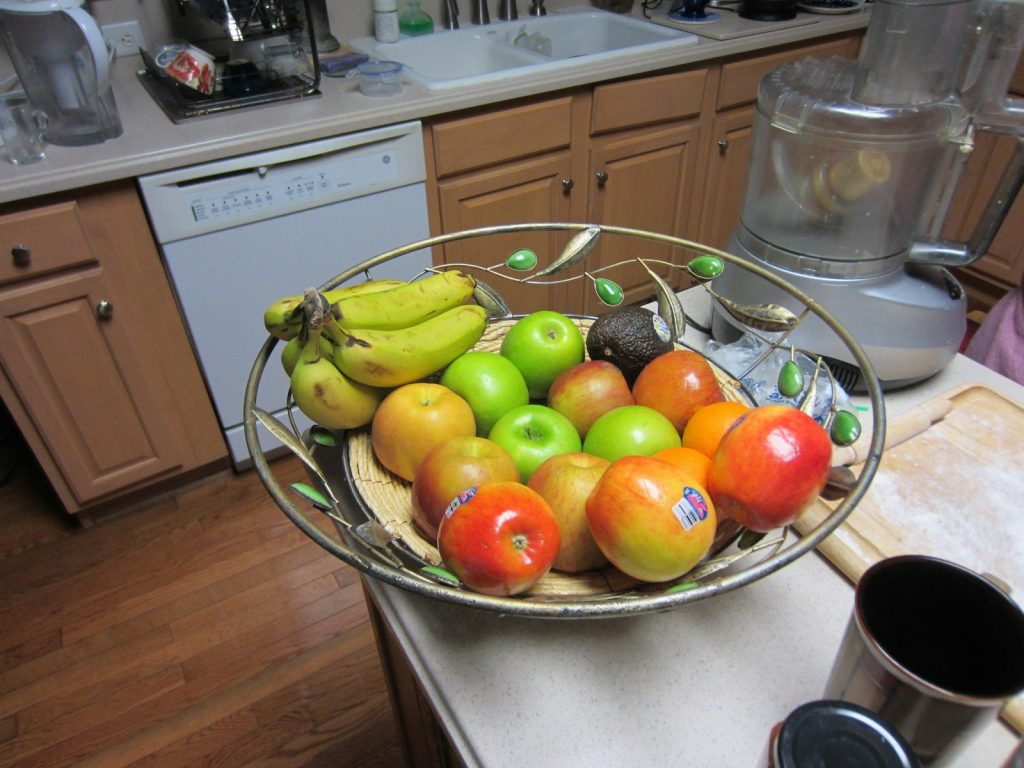A bowl of assorted fruits on a kitchen counter.