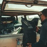 man loading black bag in back of suv