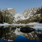 snow covered mountain near lake during daytime
