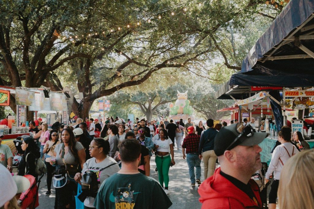 A crowd of people walking down a street next to trees