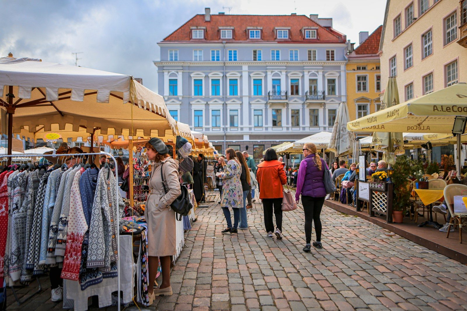 A street market bustles with people and clothing stalls.