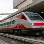 A modern red and white train at a station.