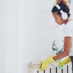 Young woman with headphones cleaning a shelf