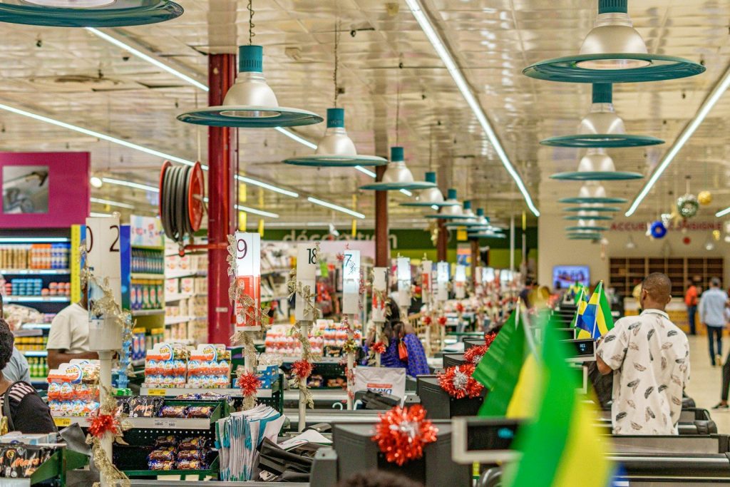 People shopping in a brightly lit supermarket aisle.