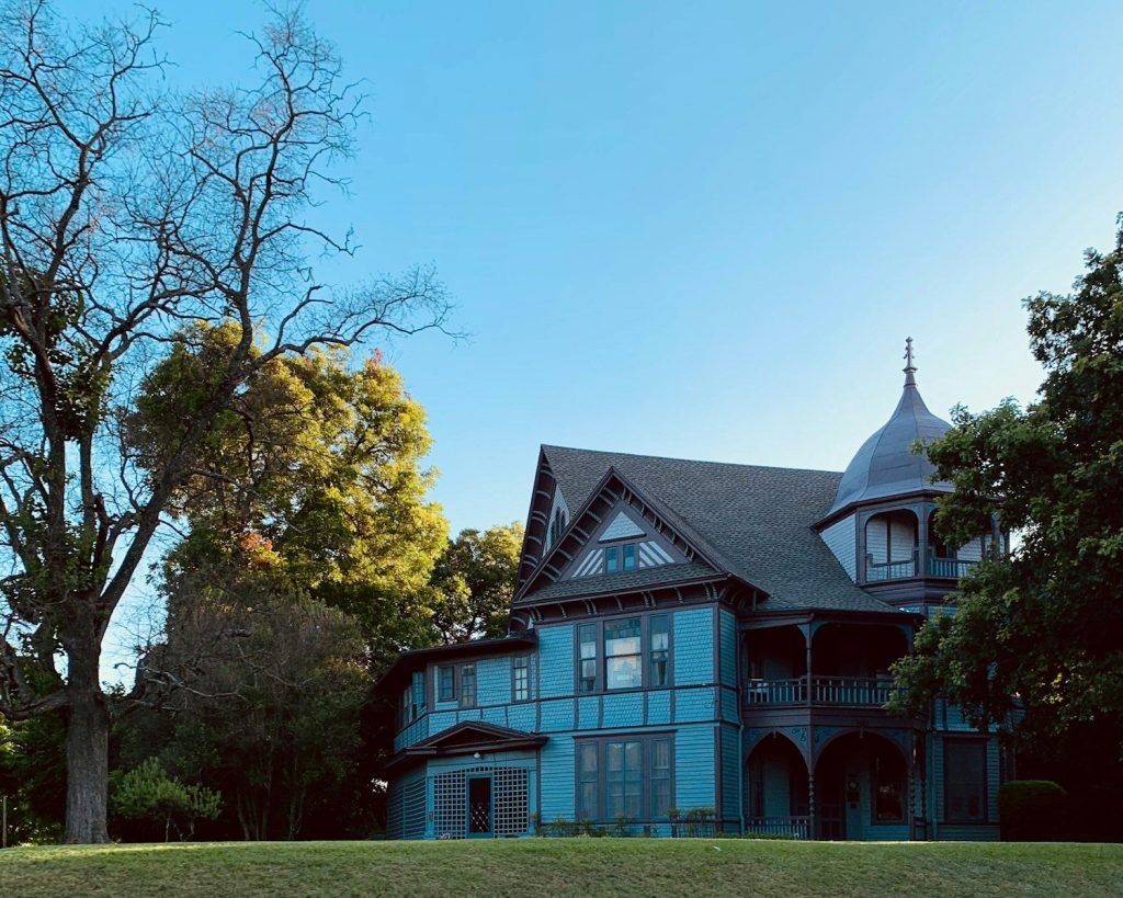 a large blue house sitting on top of a lush green field
