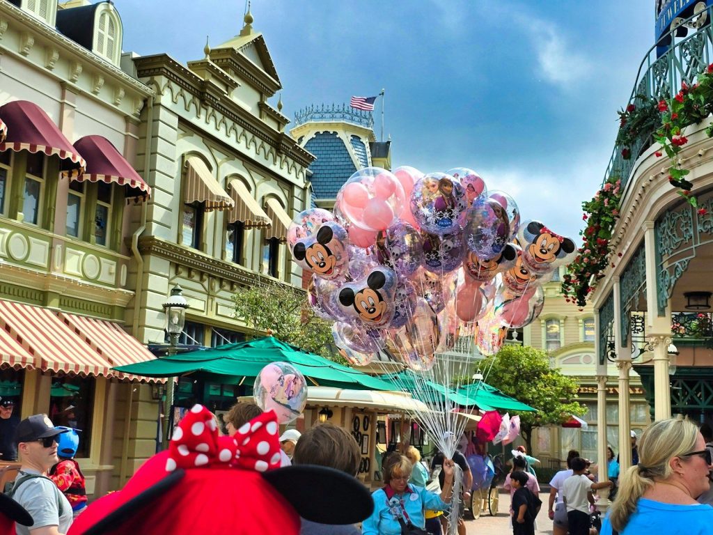 Mickey mouse balloons float down a street.