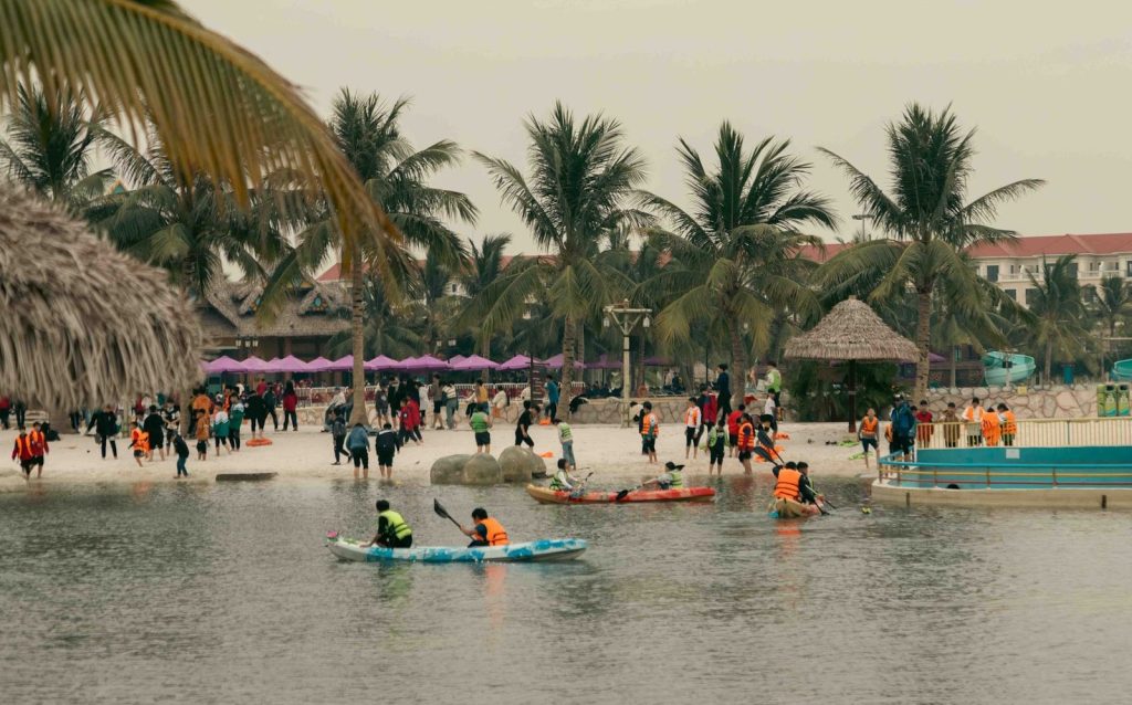 People kayaking and walking on a tropical beach resort.