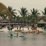 People kayaking and walking on a tropical beach resort.